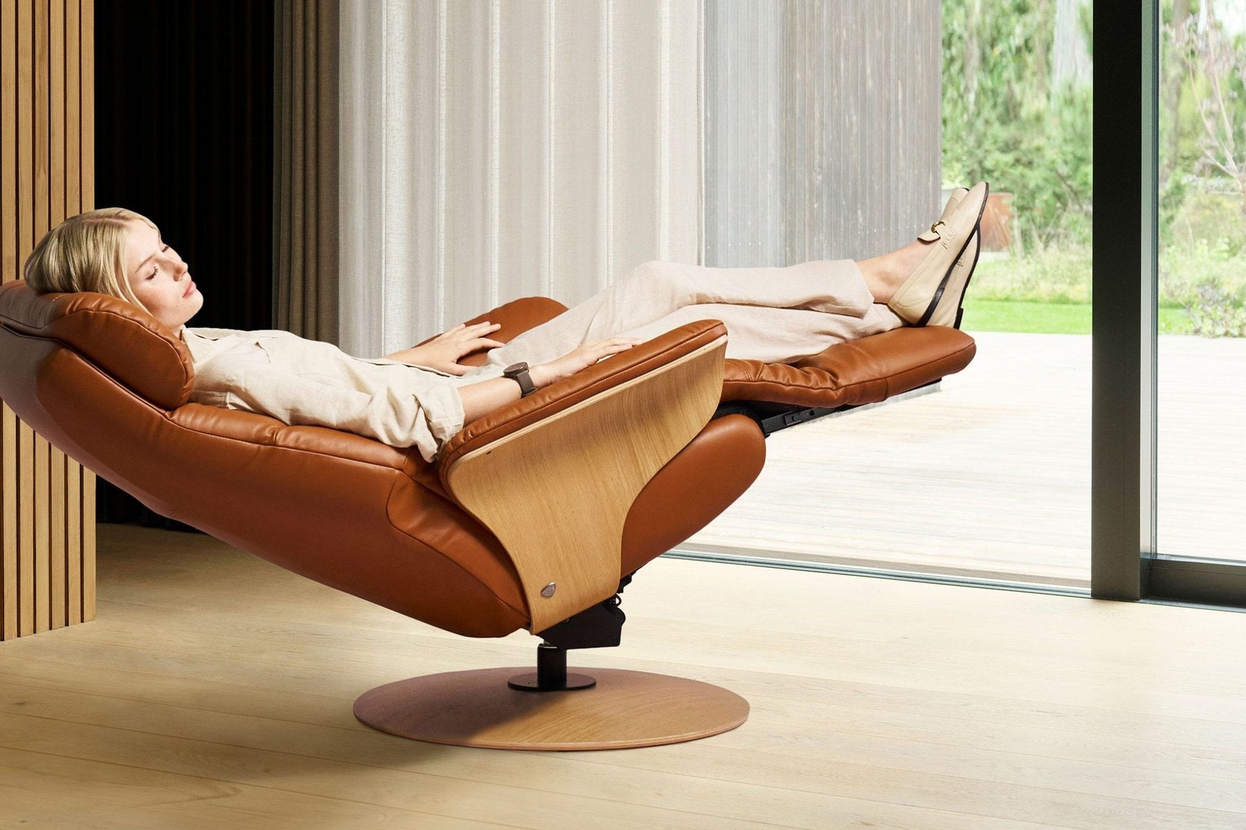 Woman fully reclined in a Stressless Adam power recliner in New Cognac leather