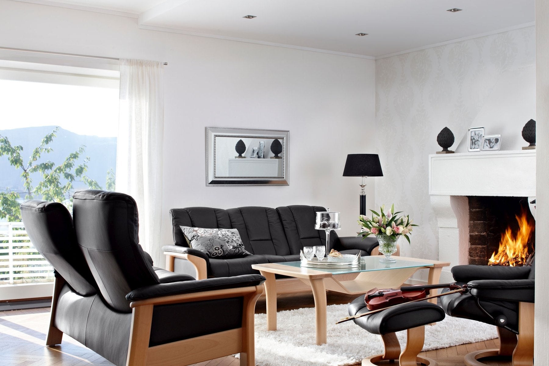 Stressless Buckingham sofa and chairs in Paloma Black leather with oak trim by a fireplace