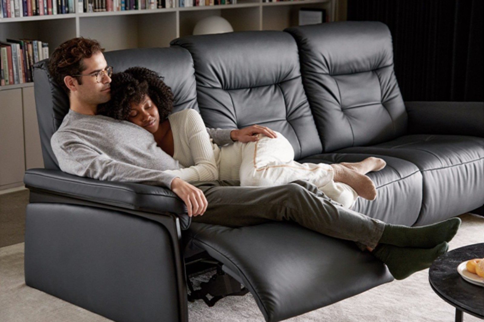 Couple relaxing on a black leather Stressless Mary reclining sofa