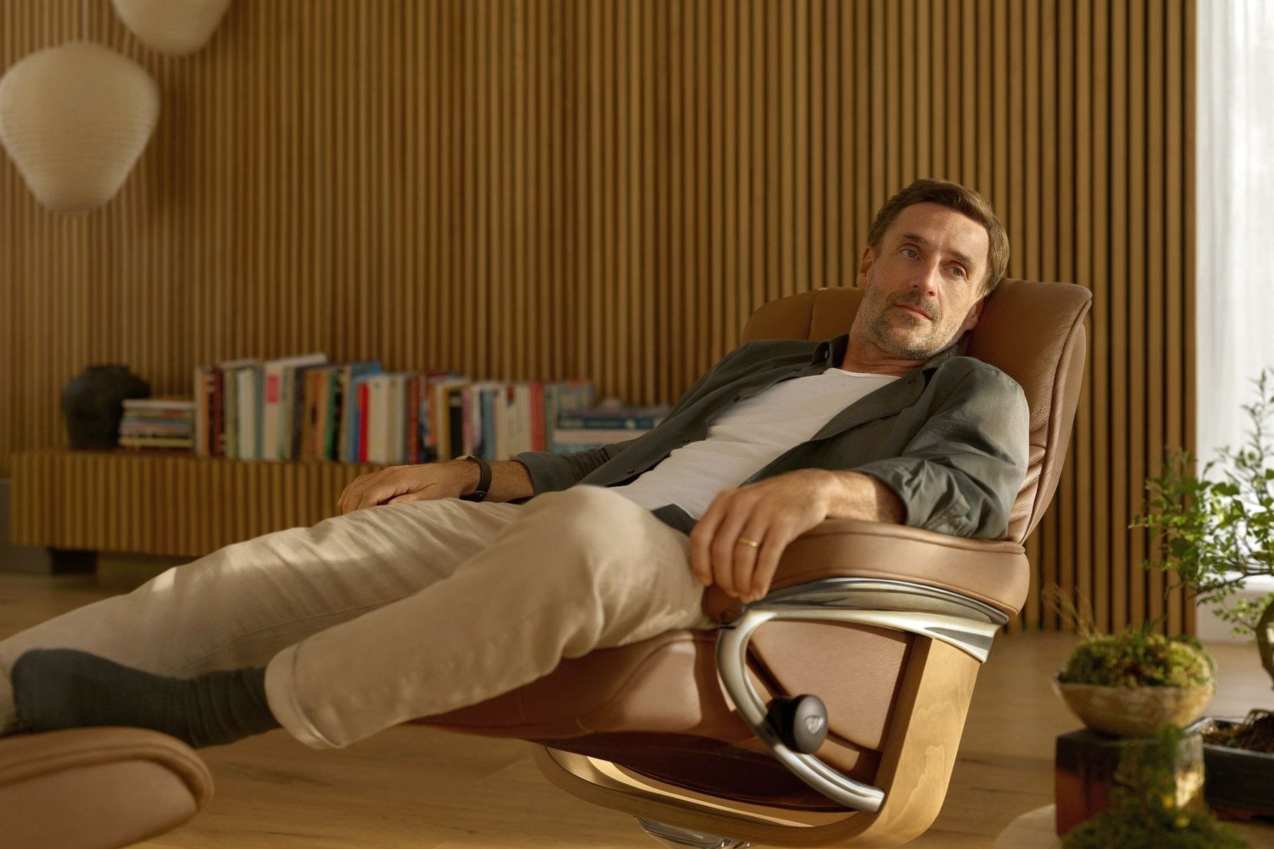 Man relaxing in a Stressless Mayfair Signature recliner in a warm wood-paneled living room