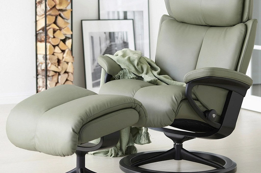 Stressless Reno Classic recliner and ottoman in sage green leather with adjustable neck support in a bright living room