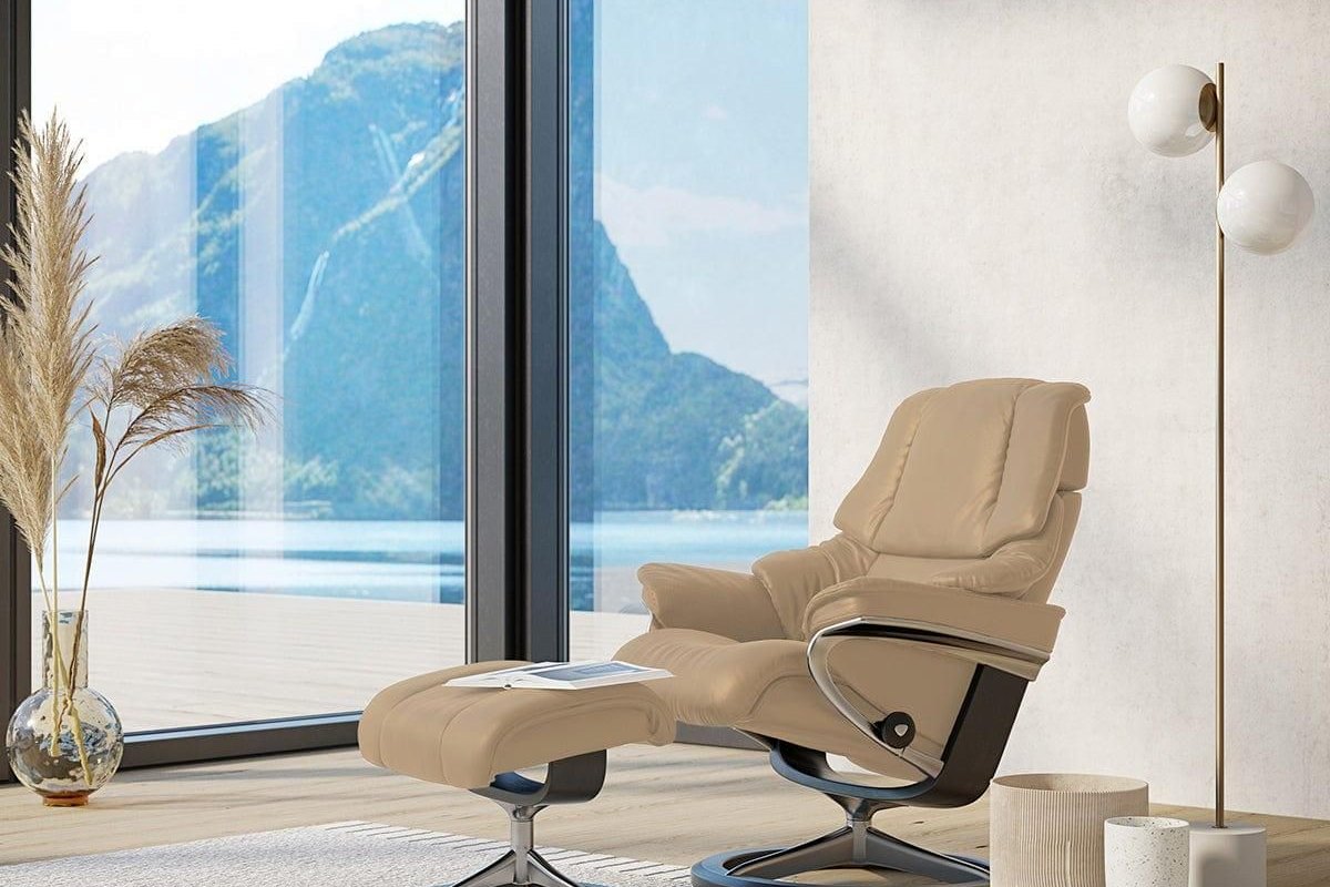 Stressless Reno Signature recliner and ottoman in beige leather by a window with a lake view