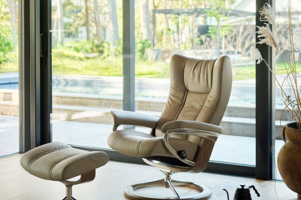 Stressless Wing Signature recliner and ottoman in light leather by a large window