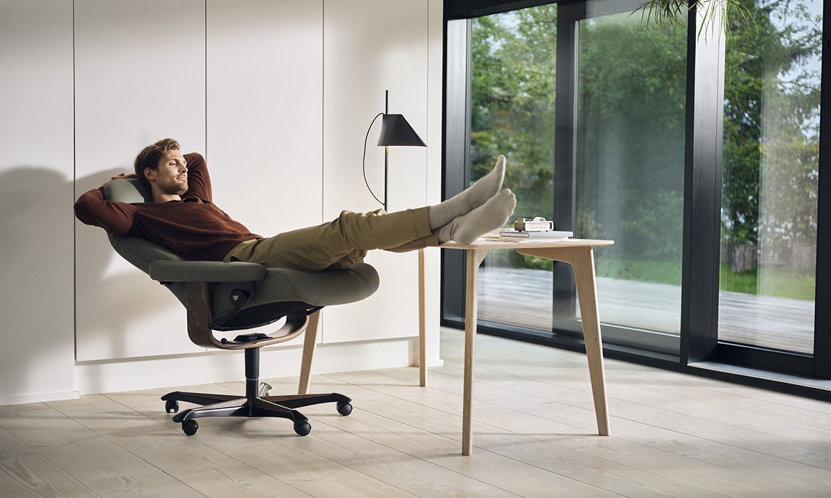 Man reclining in a Stressless Consul home office chair with feet up on the desk