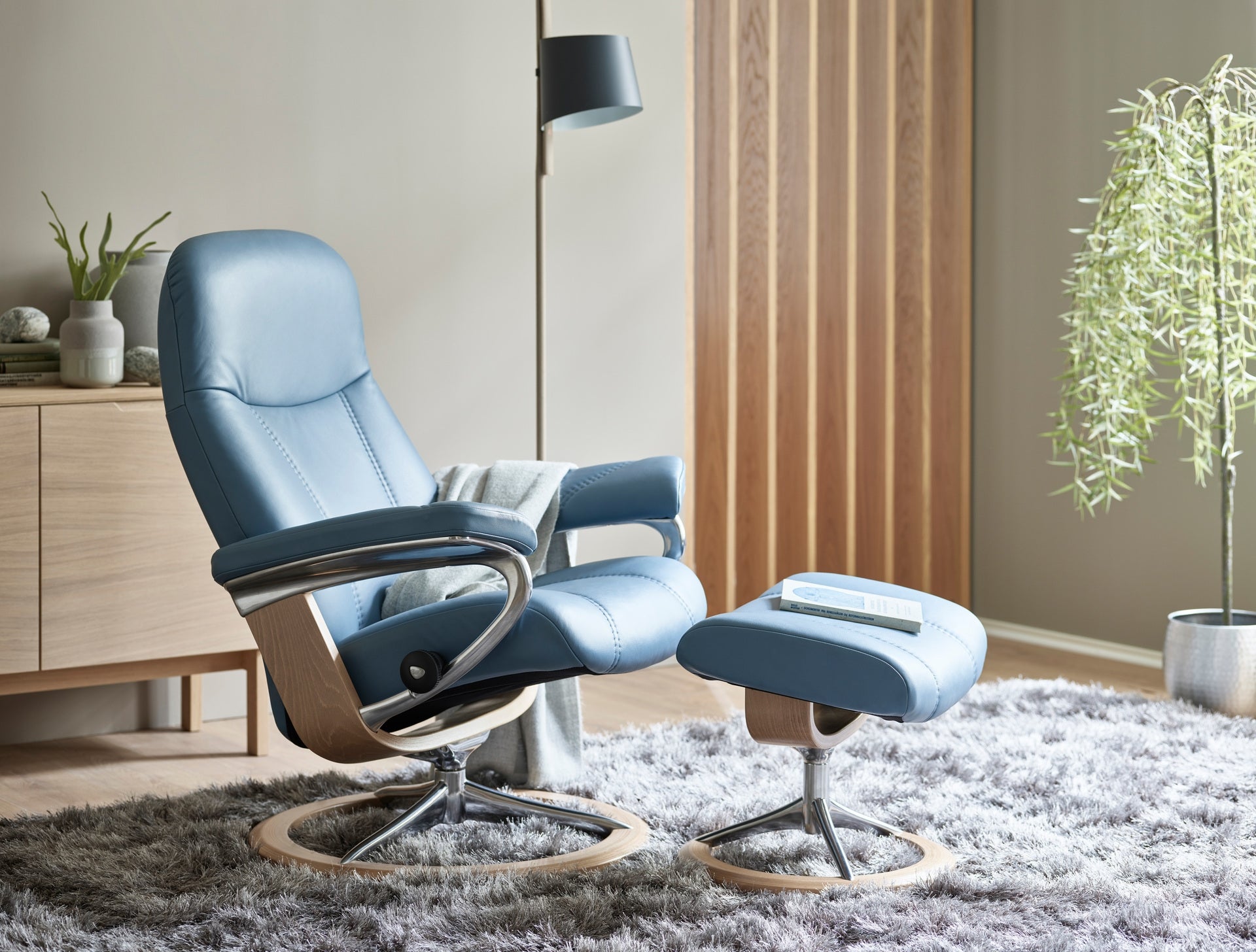The Stressless Consul Small Signature recliner in Paloma Sparrow Blue leather with Oak wood.