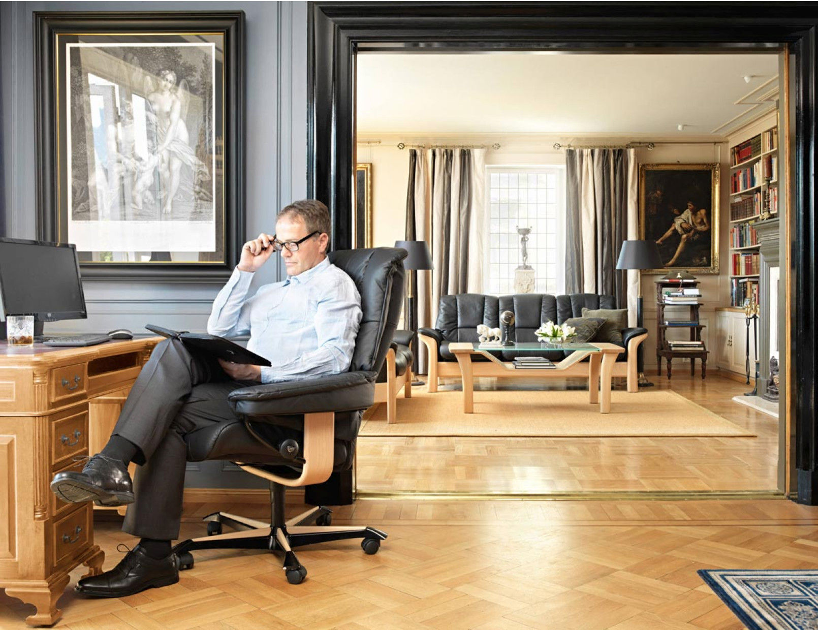 Man seated in a Stressless Mayfair home office chair in a classic home office